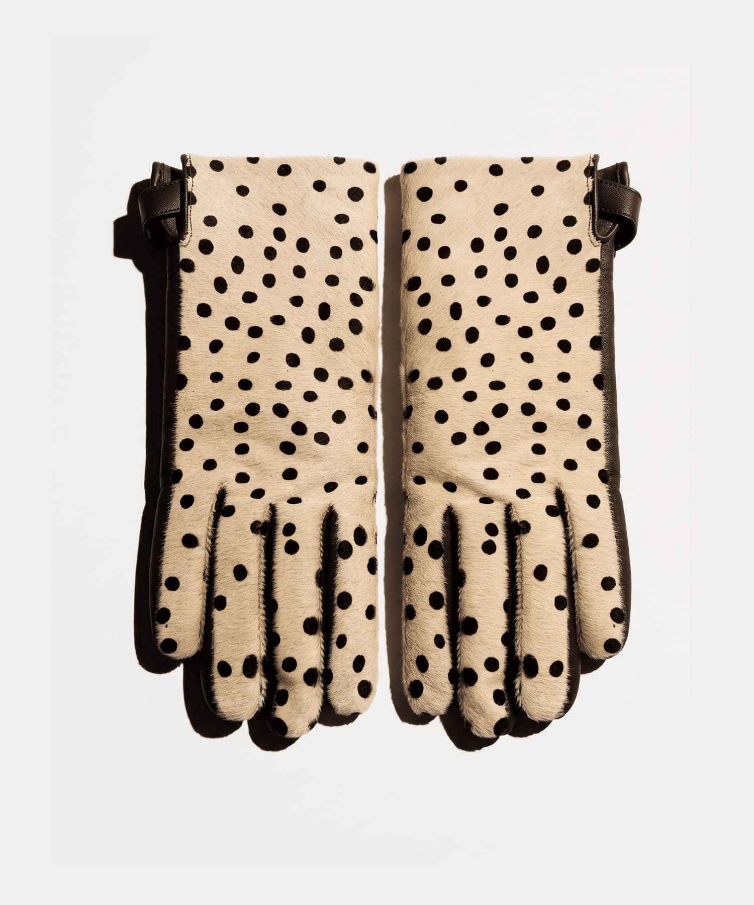 cream calf hair gloves with black spots, dark brown leather sides and a knotted strap at the wrist, front