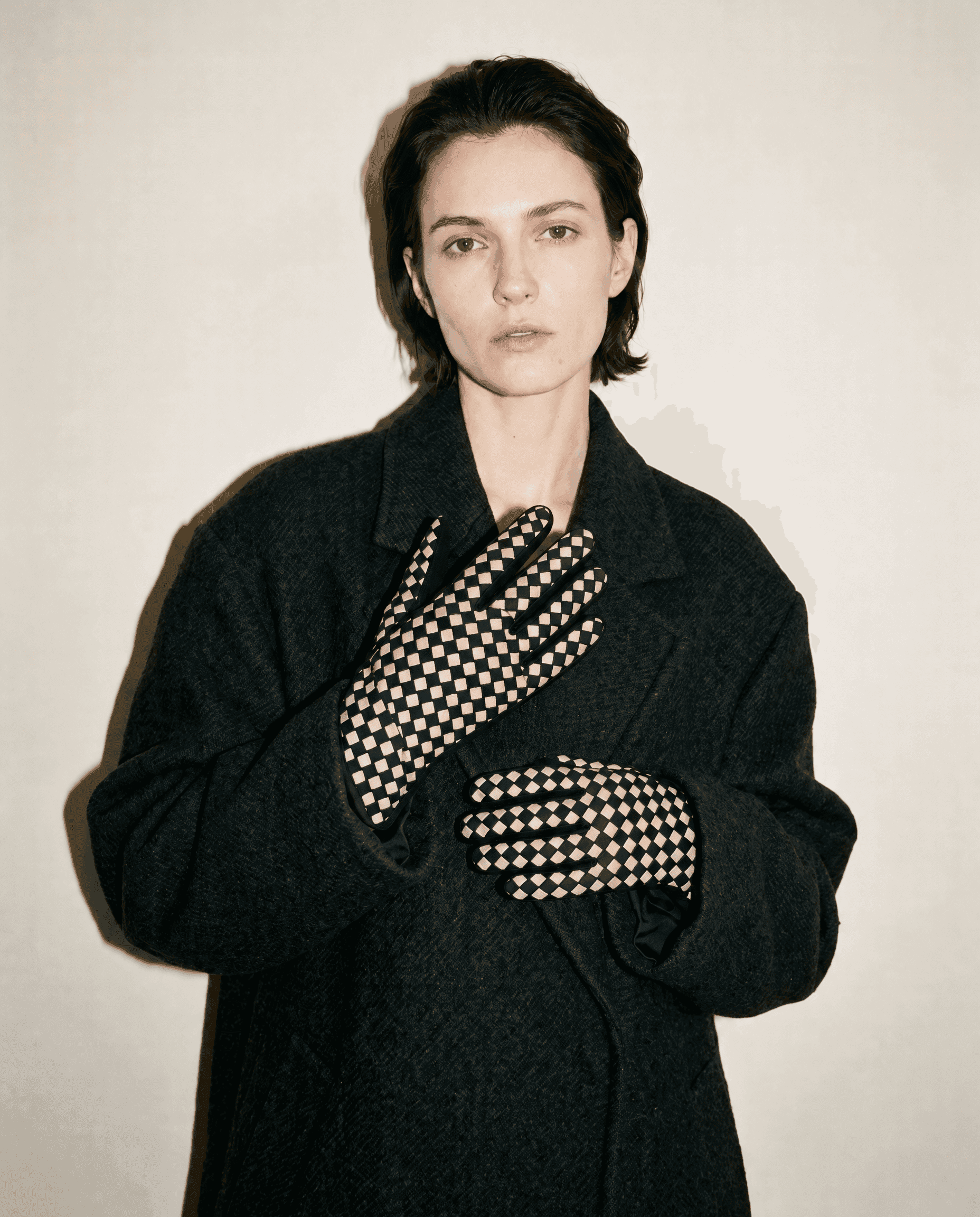 black suede gloves with a cream checkerboard back, worn