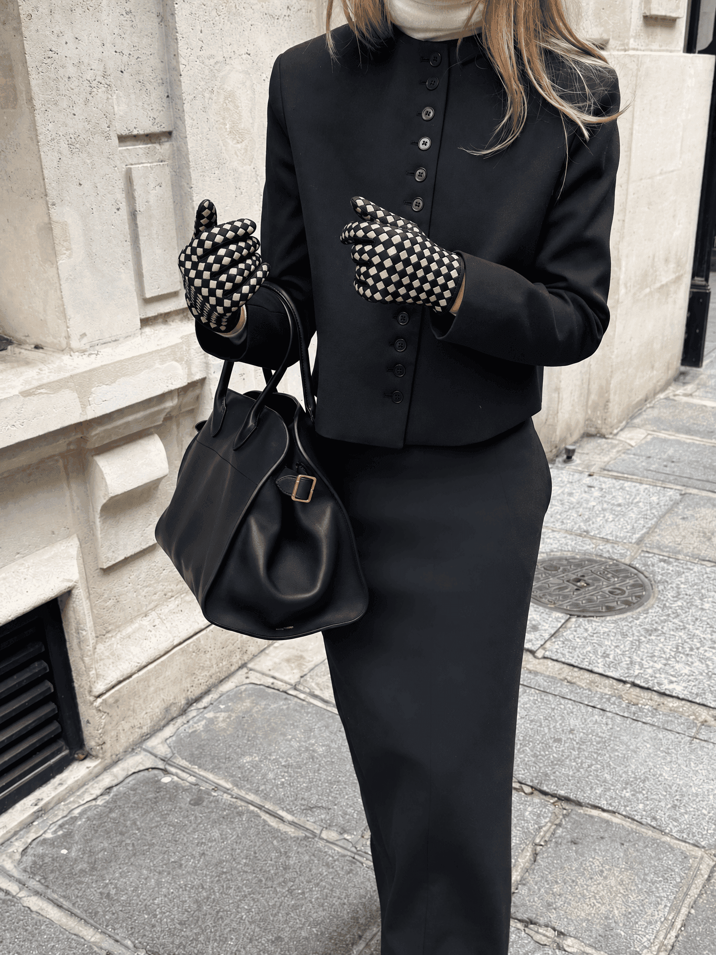 black suede gloves with a cream checkerboard back, worn